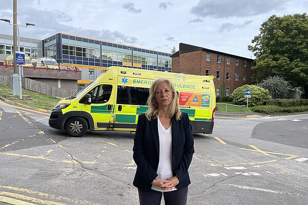 Liz stood outside hospital with ambulance