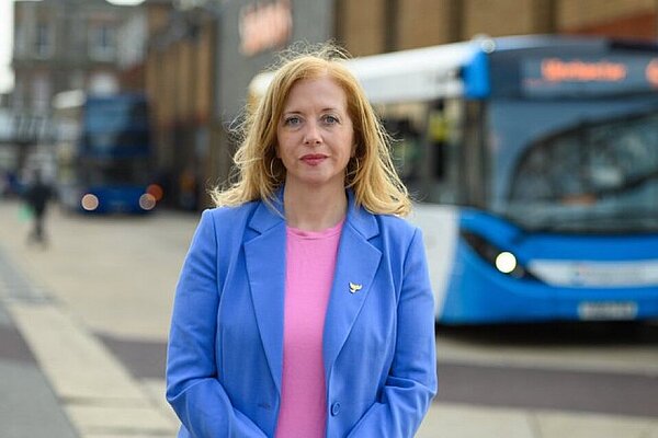 Liz stood with blue bus in Eastleigh