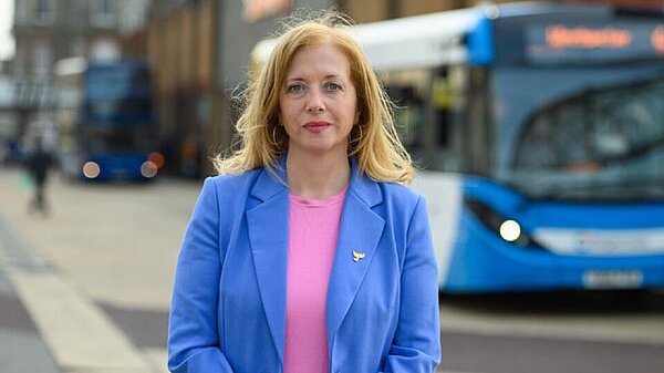 Liz J stood in front of blue bus