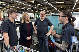 Liz speaking to four engineers in a factory