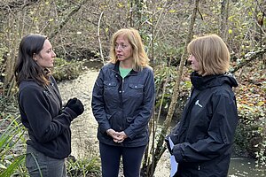 Liz stood next to a lake speaking to nature workers